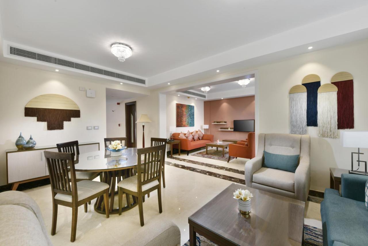 Tolip Resort El Galala Majestic Ain Soukhna Exteriér fotografie The photo shows a modern living room space that is elegantly designed. It features a seating area with a comfortable sofa and armchairs, complemented by a decorative coffee table. There is a dining table with several wooden chairs, providing a cozy a