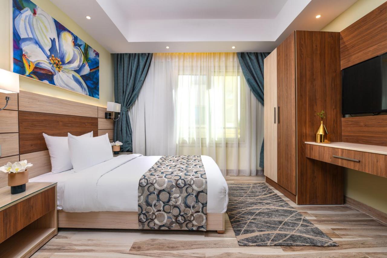 Tolip Resort El Galala Majestic Ain Soukhna Exteriér fotografie The photo shows a well-designed hotel room. It features a comfortable bed with a decorative bedspread and two pillows. There are soft curtains framing a window that lets in natural light. On one side, there is a colorful piece of artwork hanging on t