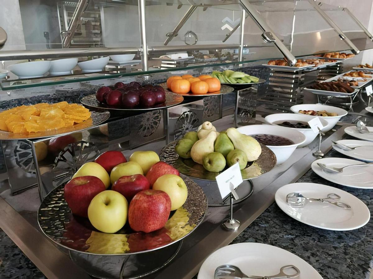 Tolip Resort El Galala Majestic Ain Soukhna Exteriér fotografie The photo displays a buffet setup featuring an assortment of fresh fruits arranged on several tiered trays. There are red and green apples, pears, grapes, and oranges. Adjacent to the fruit display, there are several bowls containing various other fo