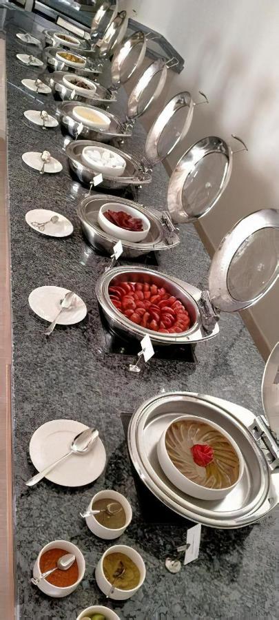 Tolip Resort El Galala Majestic Ain Soukhna Exteriér fotografie The photo shows a buffet setup featuring multiple metal serving trays on a dark granite countertop. One tray contains circular slices of food, possibly sausages or a similar dish, while another bowl holds what appears to be red food items, though it'