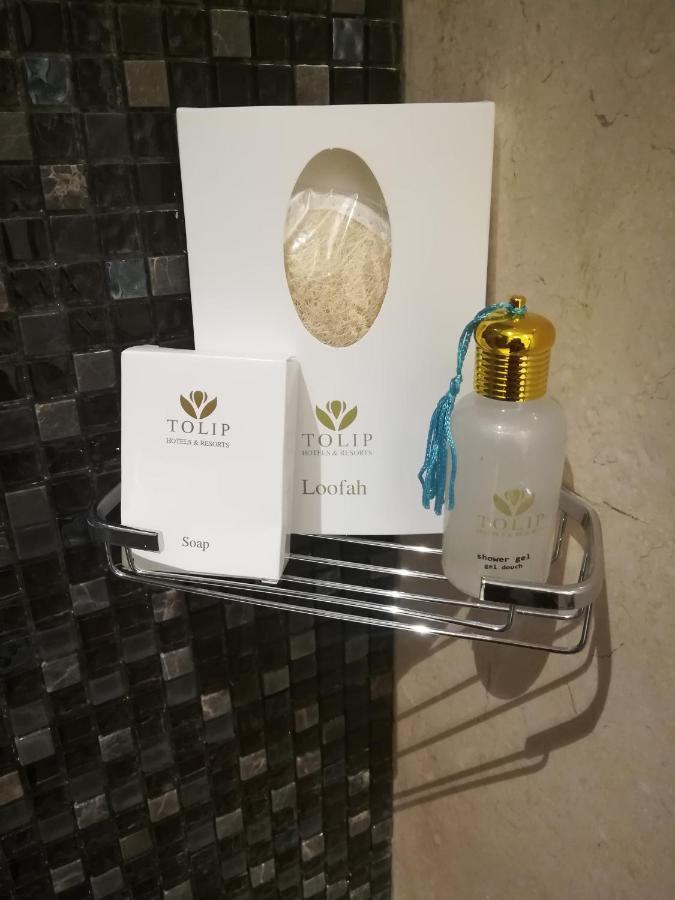 Tolip Resort El Galala Majestic Ain Soukhna Exteriér fotografie The photo shows a small metal shelf containing three items related to personal care. 

1. **Soap**: A white box labeled "TOLIP" with the word "Soap" visible on the front.
2. **Loofah**: A package with the same "TOLIP" branding, containing loofah.
3. 